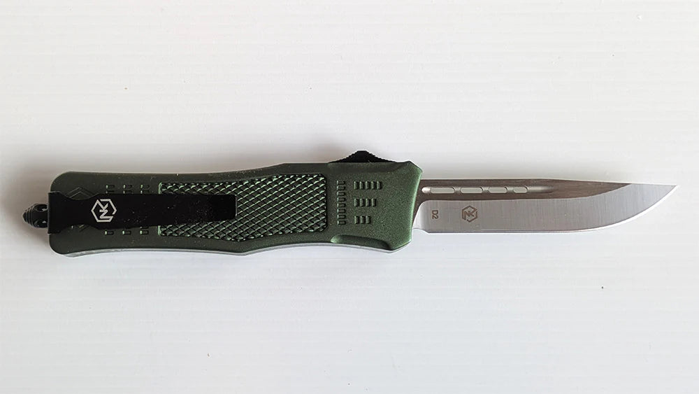 Large, lightweight Griffin knife. The blade comes standard in a D2 steel with a Drop Point blade with a non-serrated edge. The handle is a green ultralight anodized aluminum with a black switch. There is a belt clip for ease of carrying as well as glass break for safety.