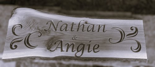 Wooden plaque with engraved names 'Nathan & Angie' on a wooden surface.