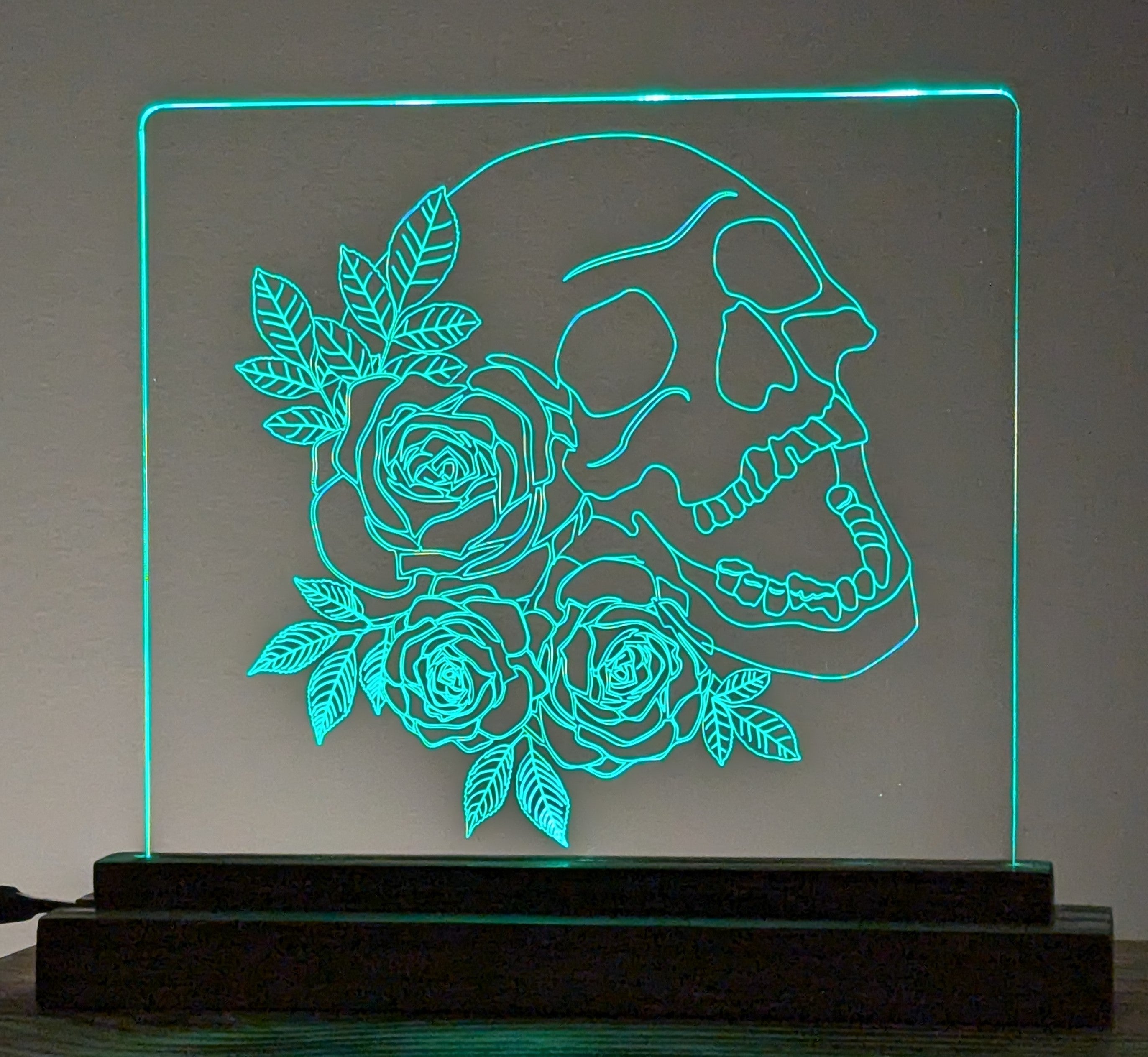 Decorative LED sign with skull and roses design on a gray background