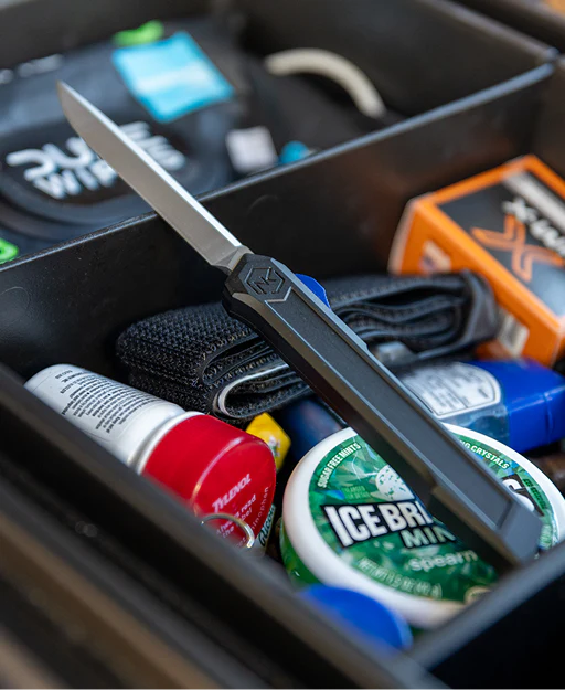 Knife in a compartment with various items including a can of ice cream.